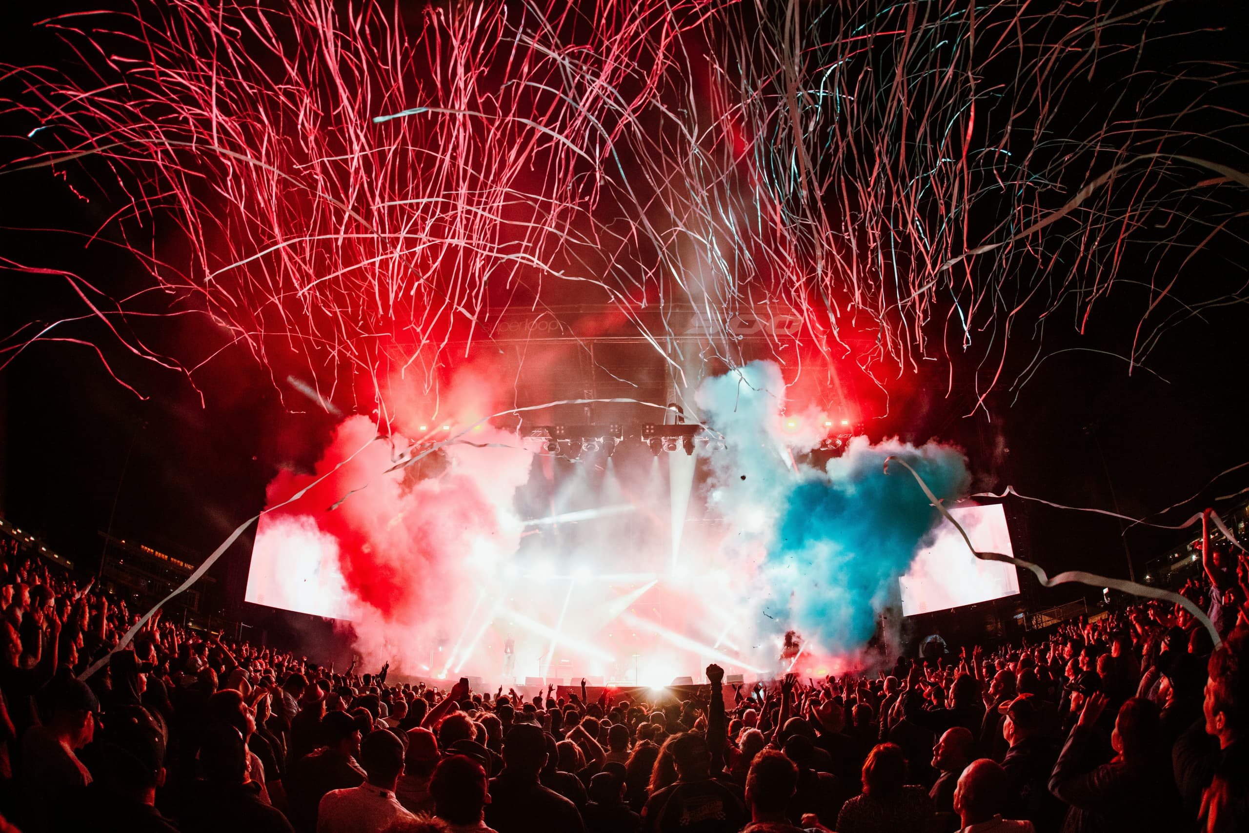 Fireworks and coloured smoke over a packed festival crowd at a Flipside event