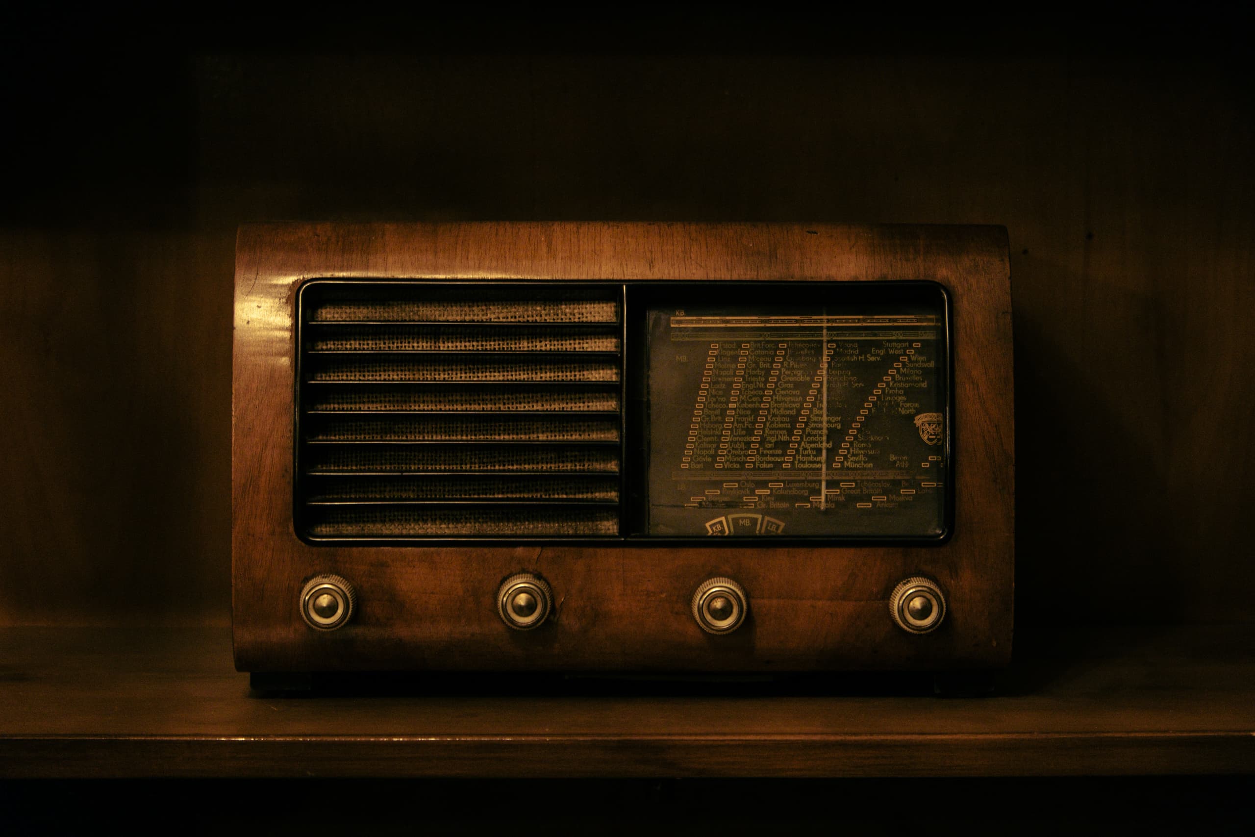A glowing vintage valve radio on a dark wooden cabinet